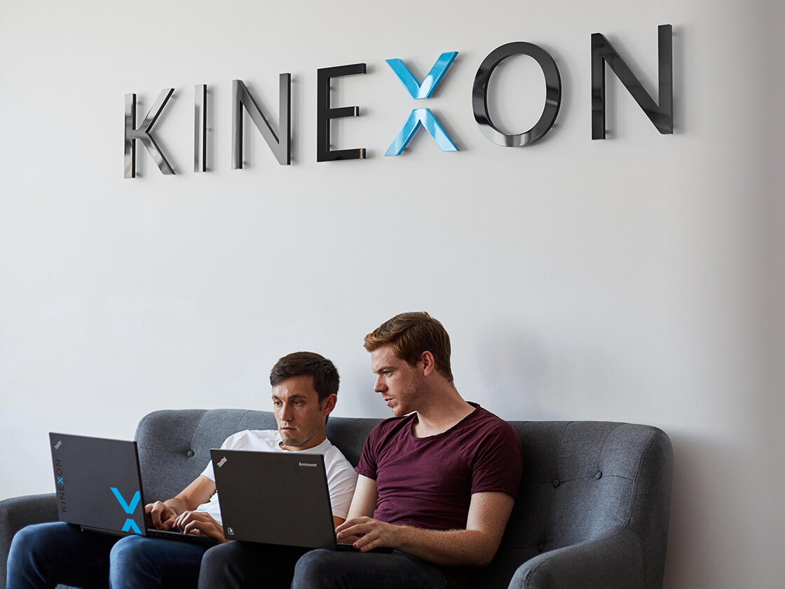 Two Kinexon employees working on a sofa together.